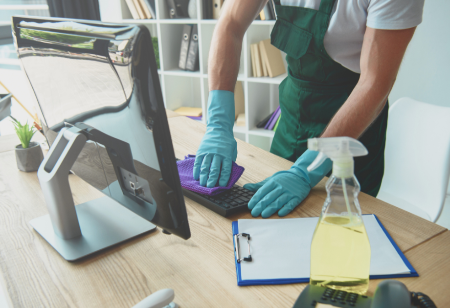 a gloved person wipes a keyboard with a clothe in an office