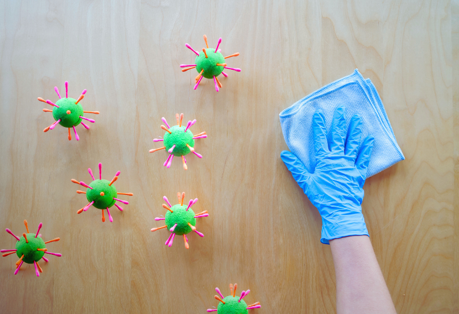 A hand in a glove cleaning a surface with a cloth