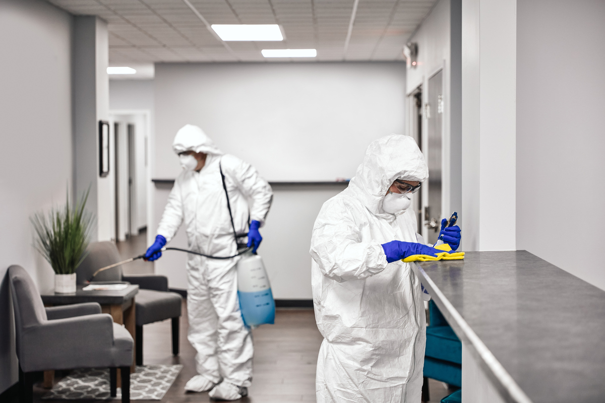 two people in bio suits cleaning an office